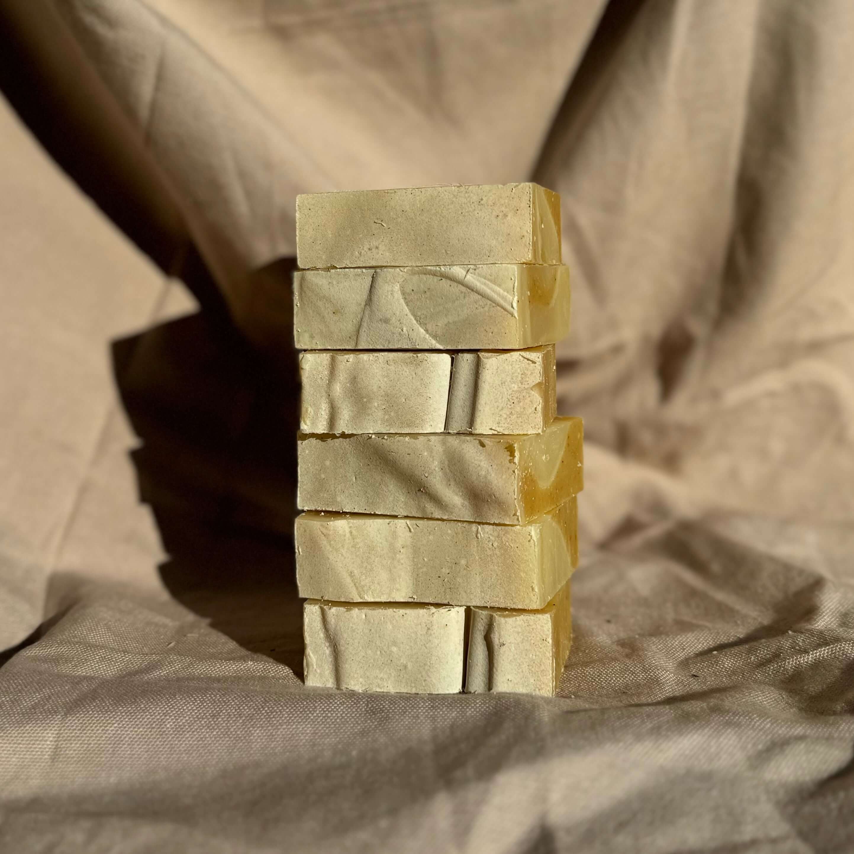 Patchouli & Ylang Ylang Body Bar stacked natural soap bars with patchouli oil and turmeric on neutral fabric background