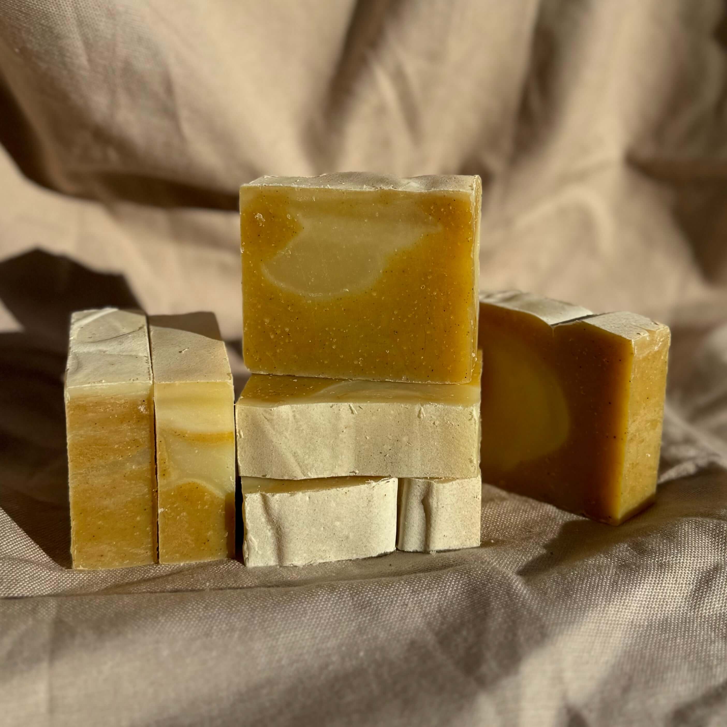Patchouli & Ylang Ylang Body Bar natural soap bars stacked on fabric, nourishing earthy turmeric and patchouli body bar
