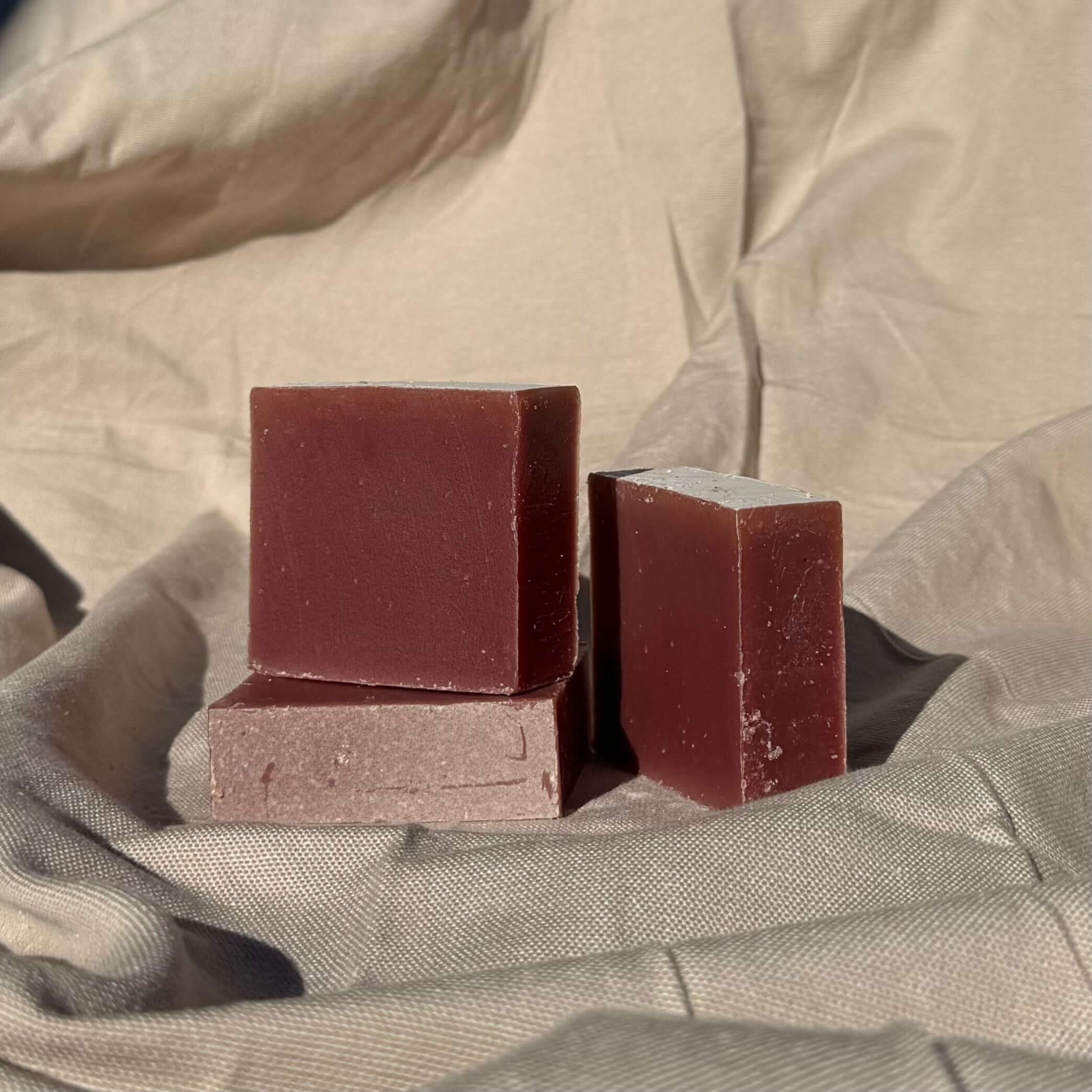 Cedar Wood & Frankincense Soap Bar with french red clay stacked on neutral fabric background