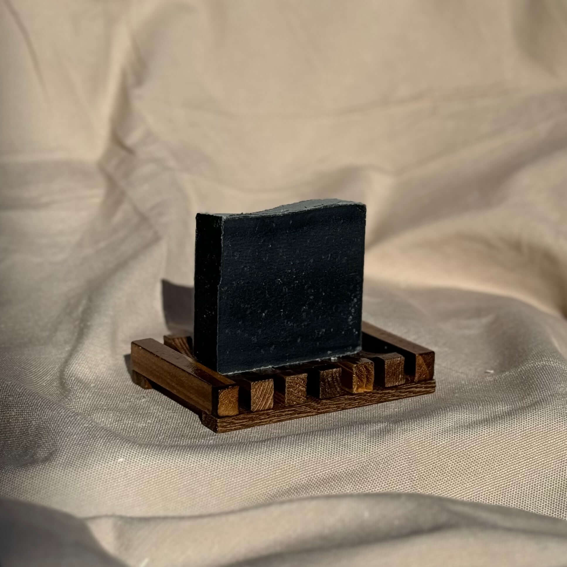 Detoxifying Charcoal Cleansing Bar displayed on wooden soap dish for deep pore cleansing and skin purification