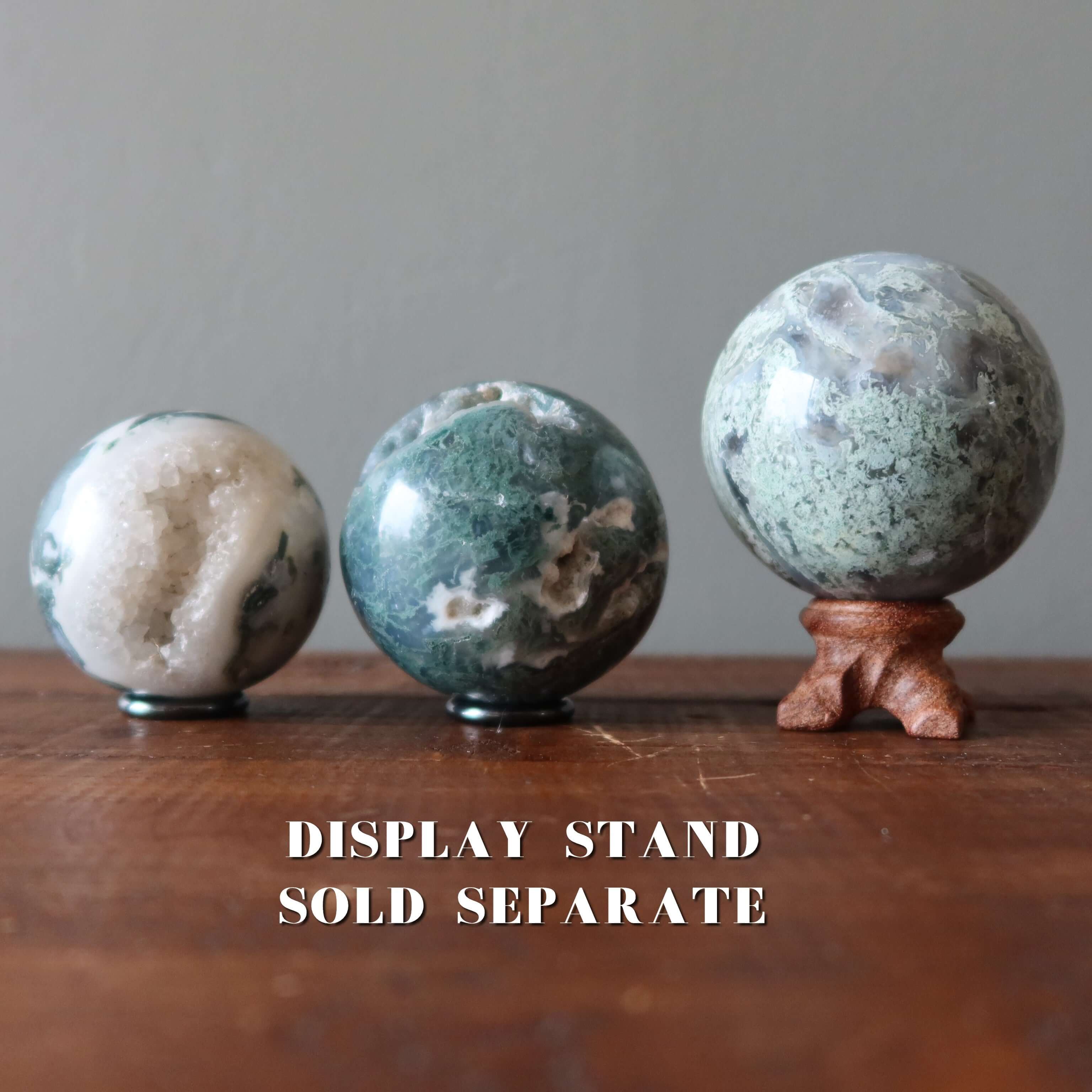 Moss Agate sphere crystal balls on wooden table, large Moss sphere on separate display stand