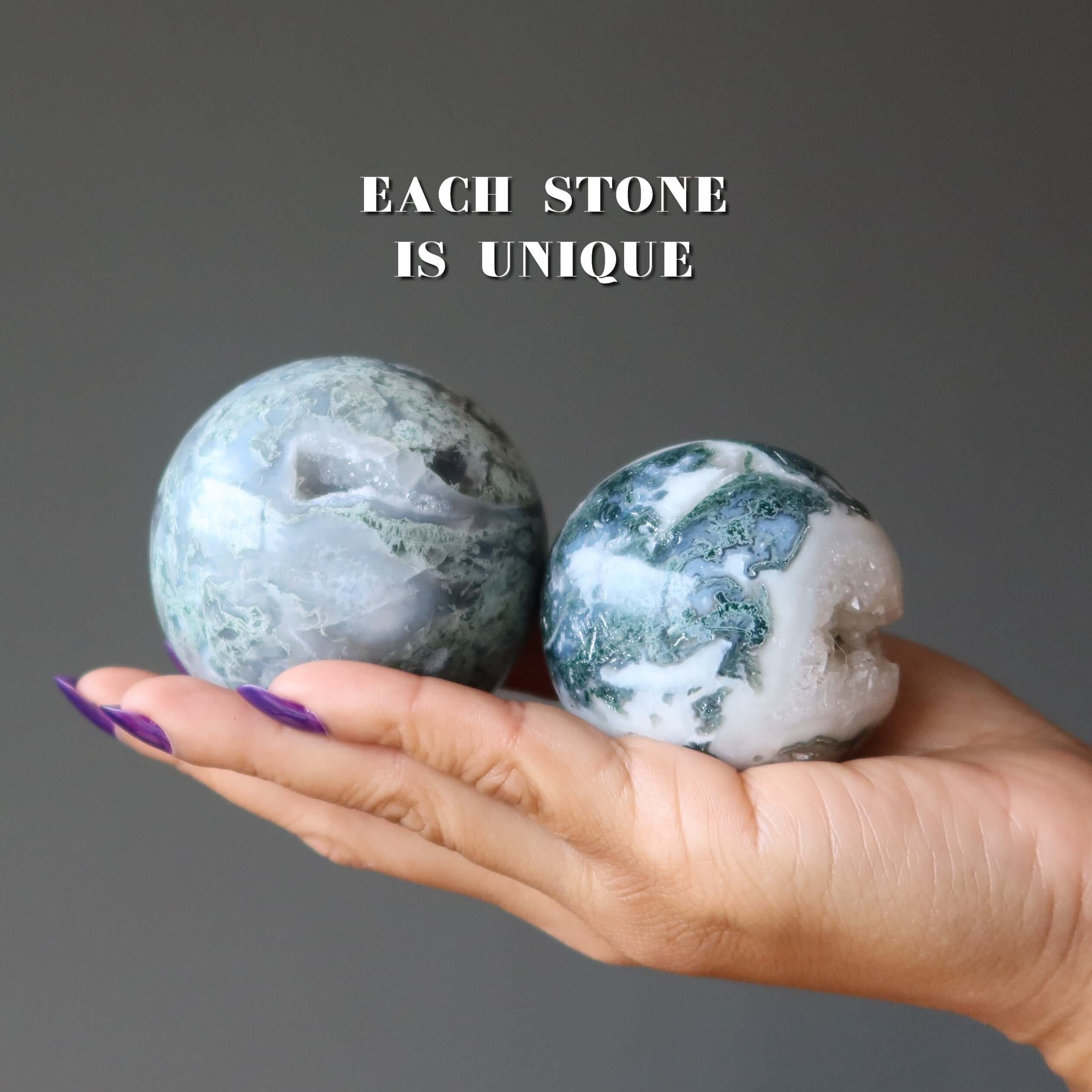 Hand holding two Moss Agate crystal spheres with unique green jungle cave patterns, caption reading each stone is unique