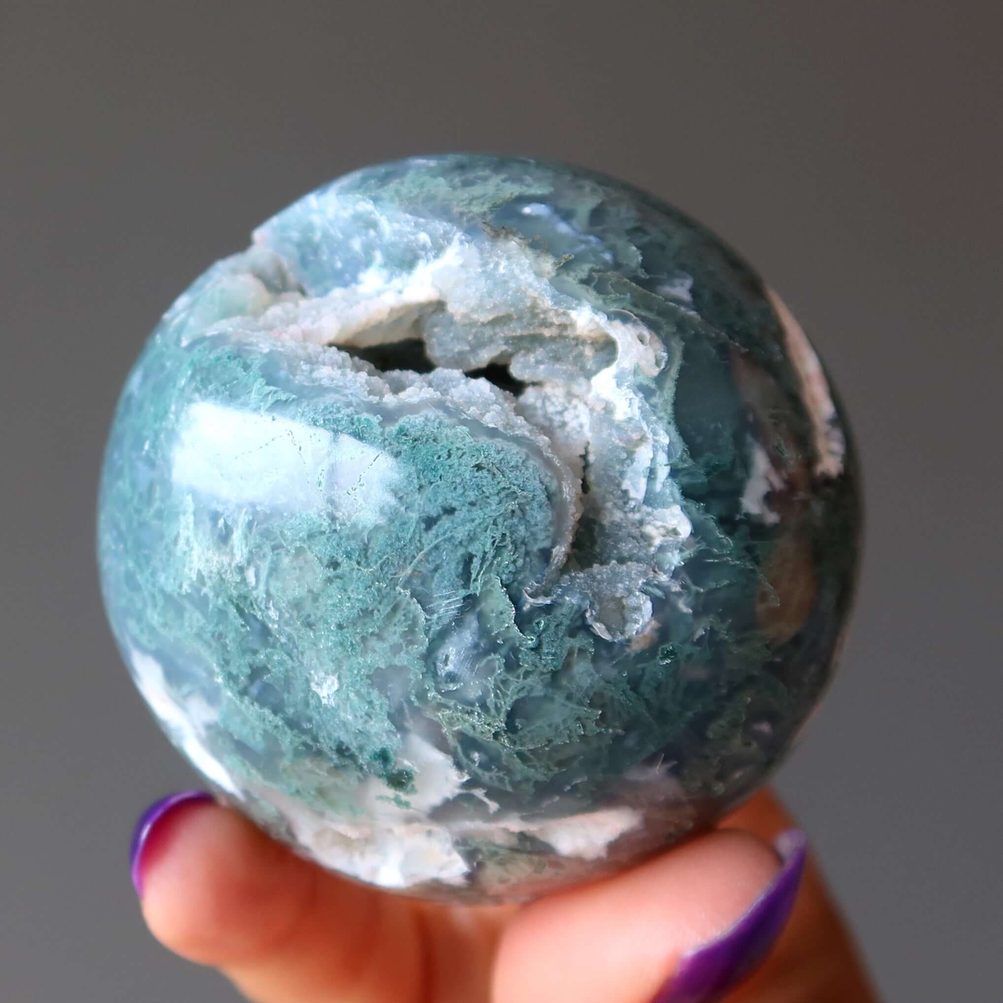 Moss Agate sphere crystal ball in hand, green jungle cave style gemstone for spiritual meditation with Moss energy