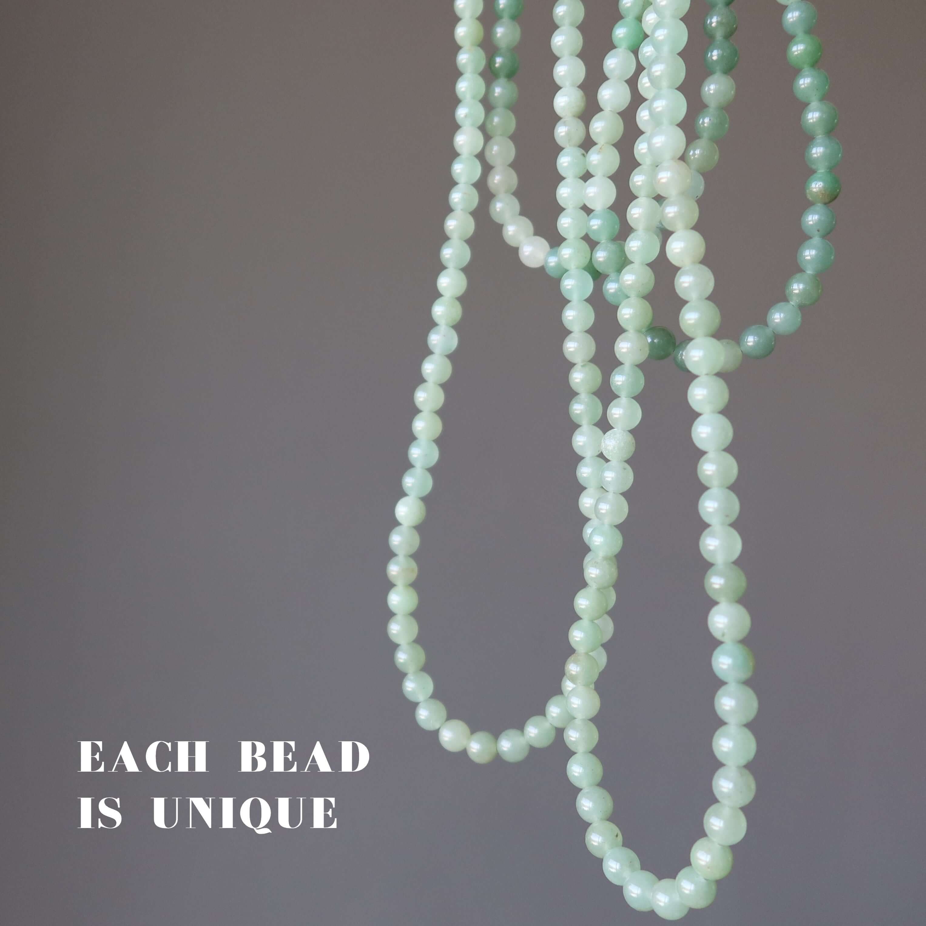 Green aventurine necklace strands showing unique round beads in soft green tones against grey background
