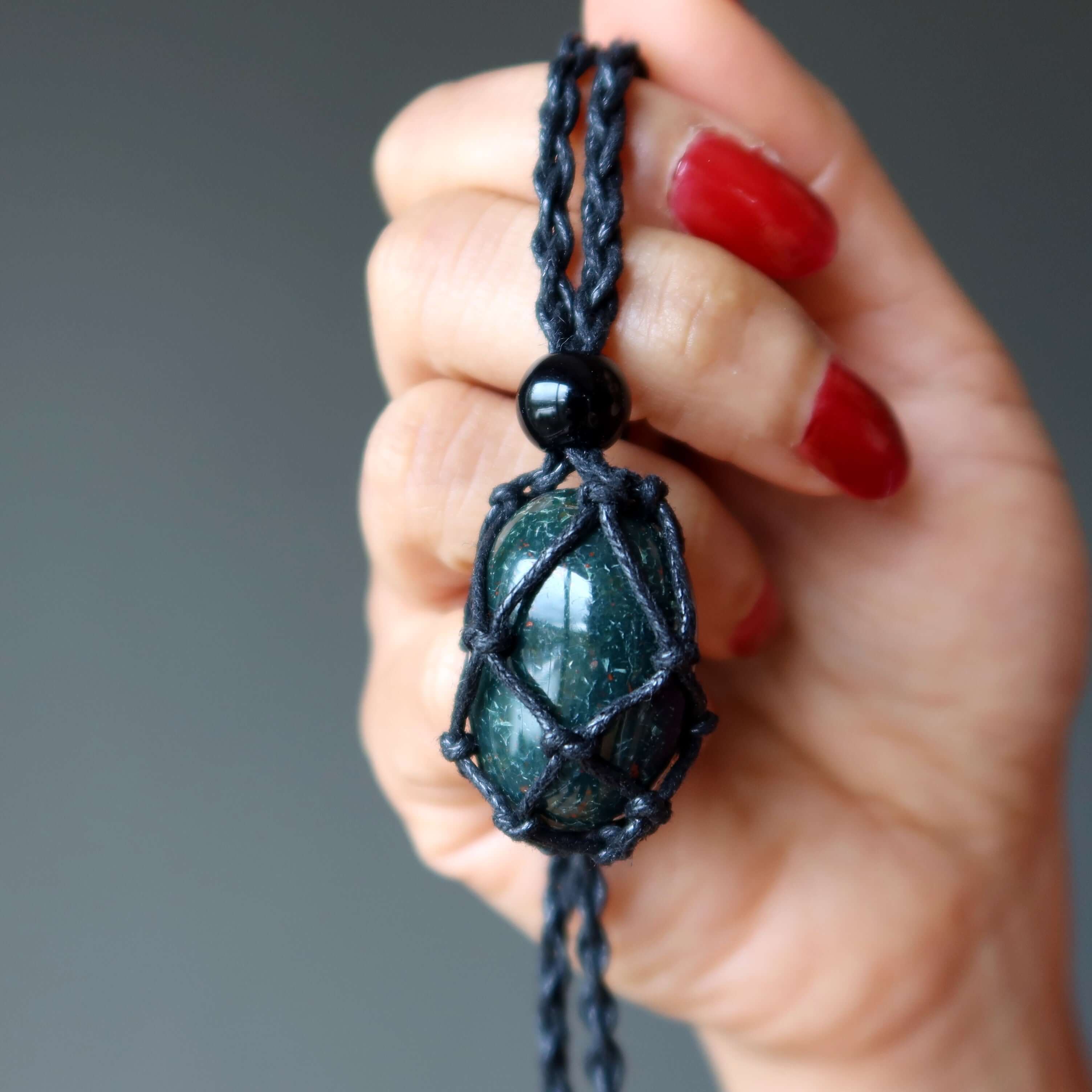 Bloodstone necklace courage carrier macrame netted gemstone pendant held in hand with red nails