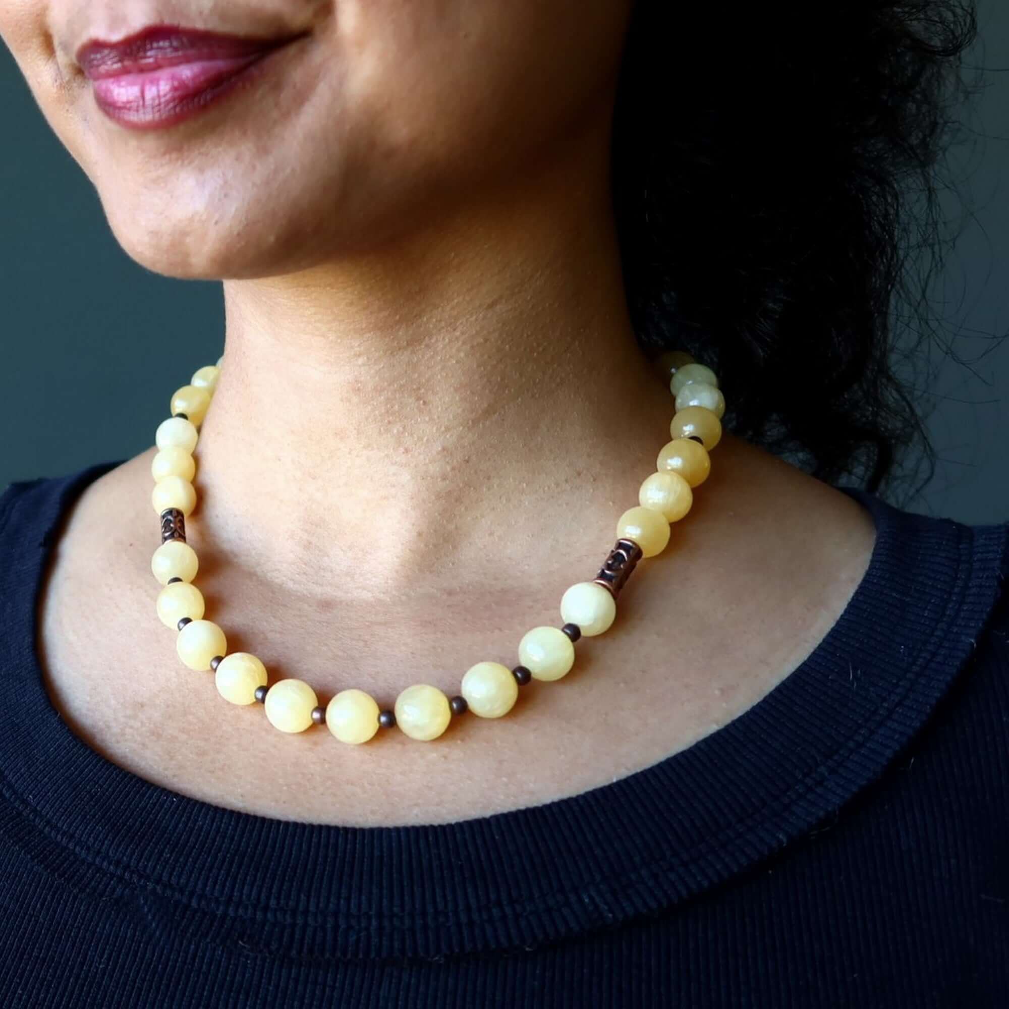 Yellow Calcite necklace with 11-12mm beads and copper accents worn on woman’s neck
