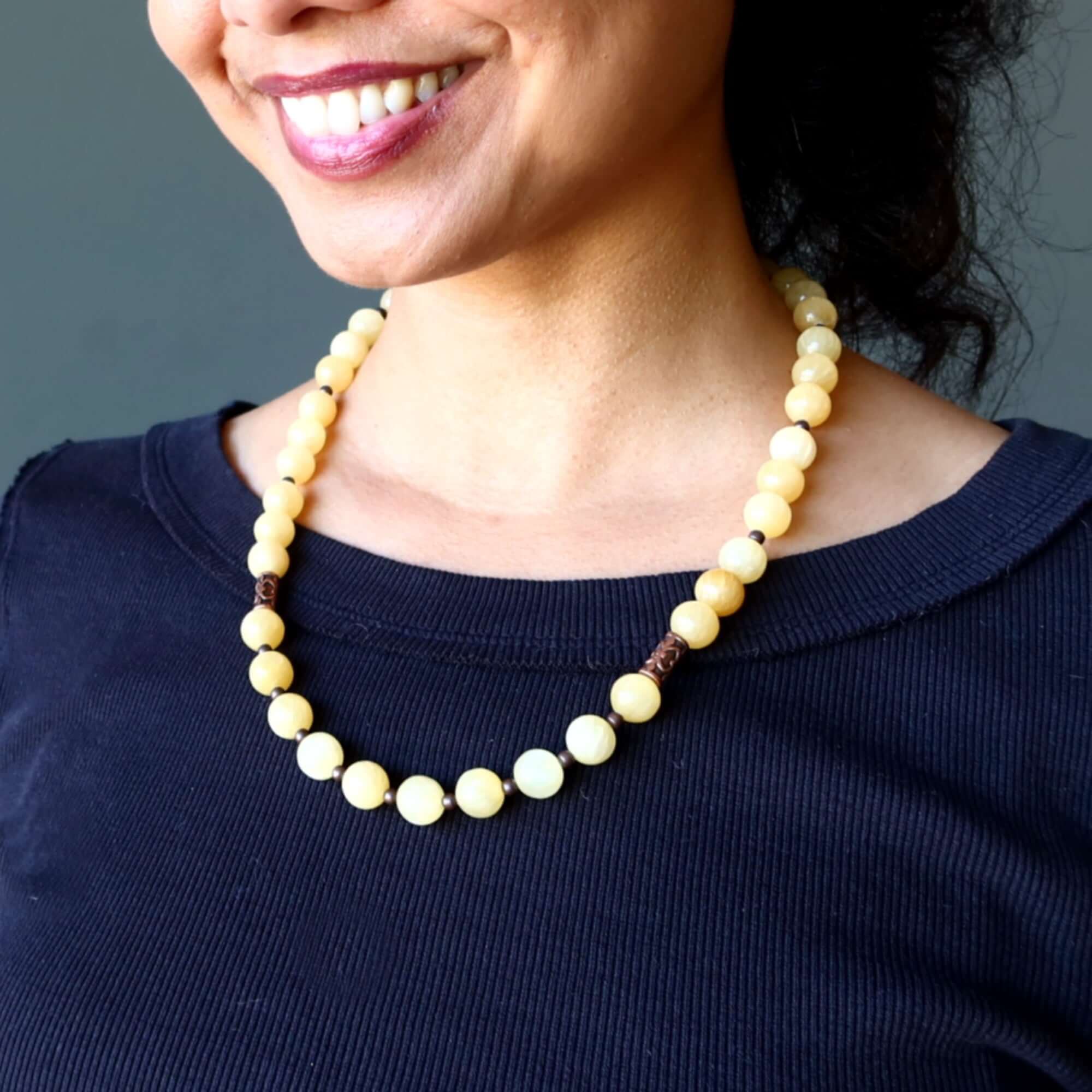 Woman wearing Yellow Calcite necklace with round 11-12mm stones and copper accents against a dark top