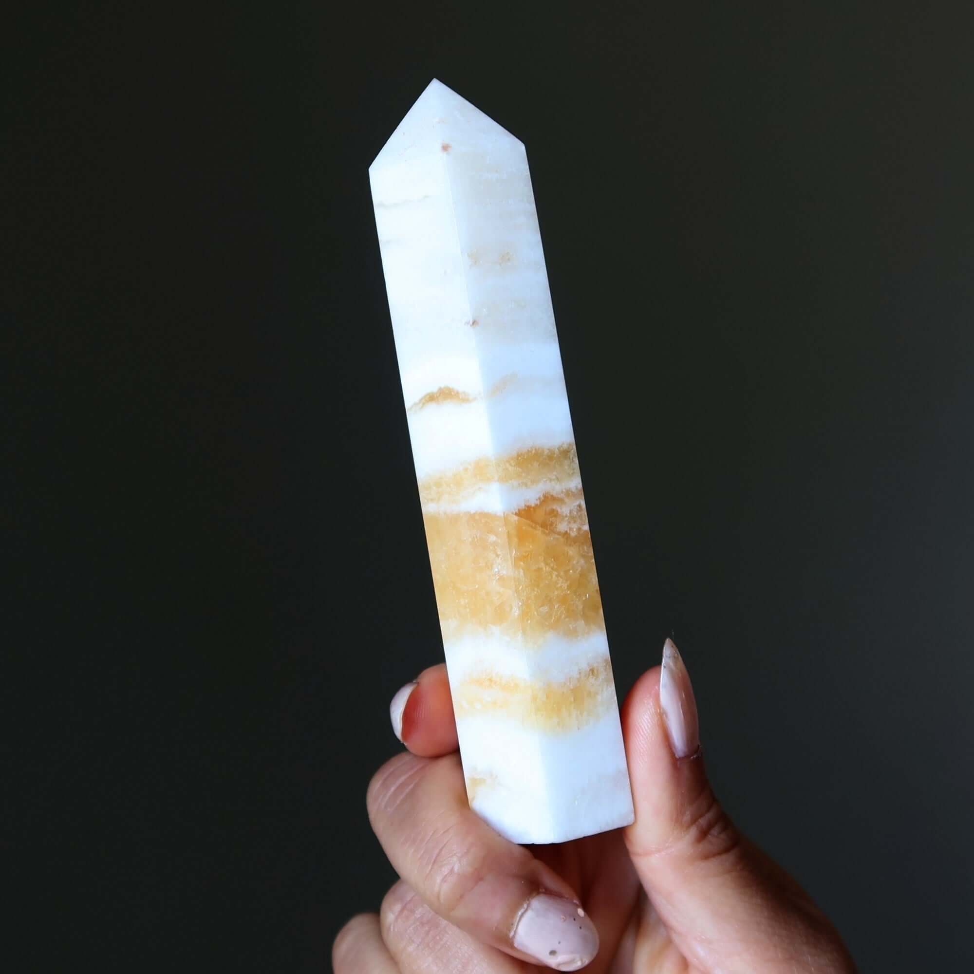 Orange Calcite tower wand crystal point held in hand, beacon of confidence and Solar Plexus energy