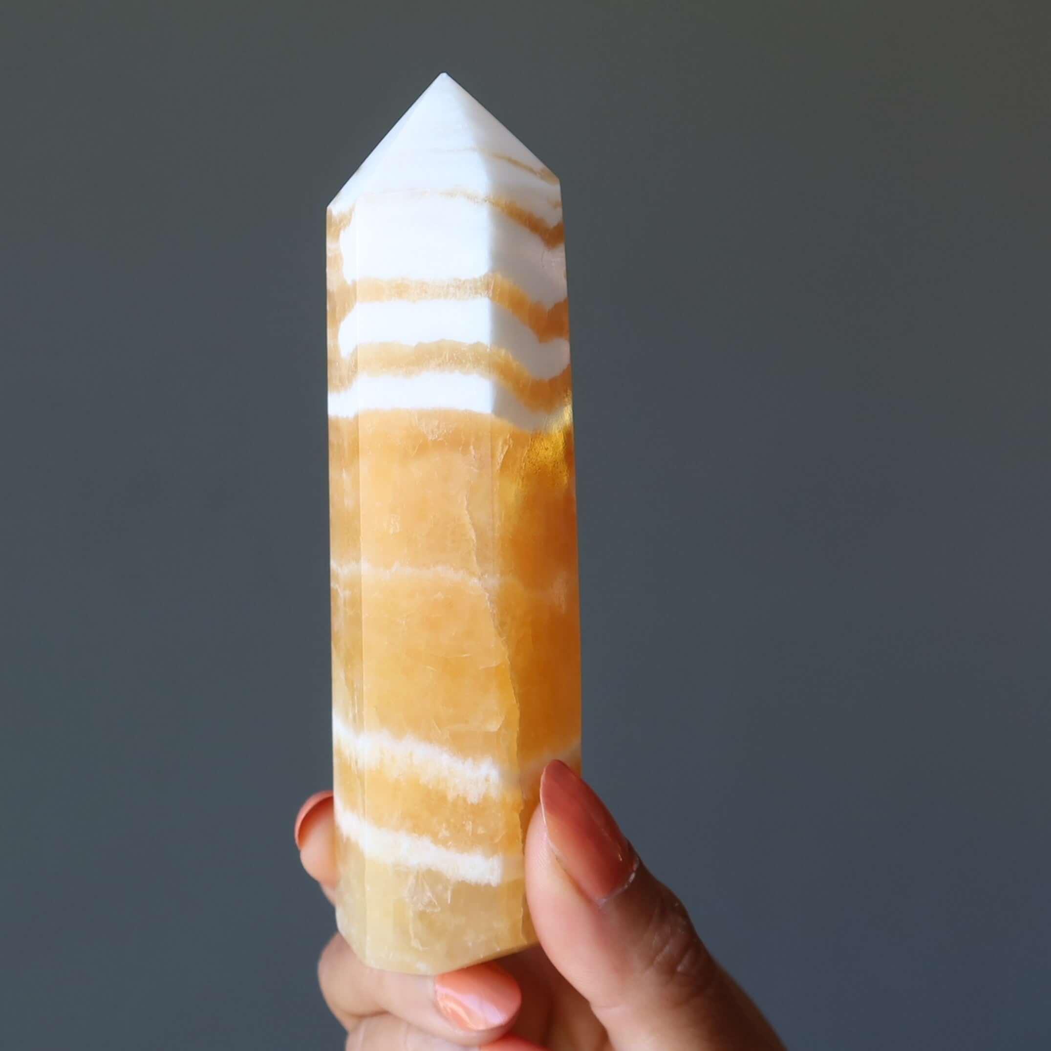 Orange Calcite tower wand crystal held in hand, striped confidence-boosting Orange point for Solar Plexus chakra energy