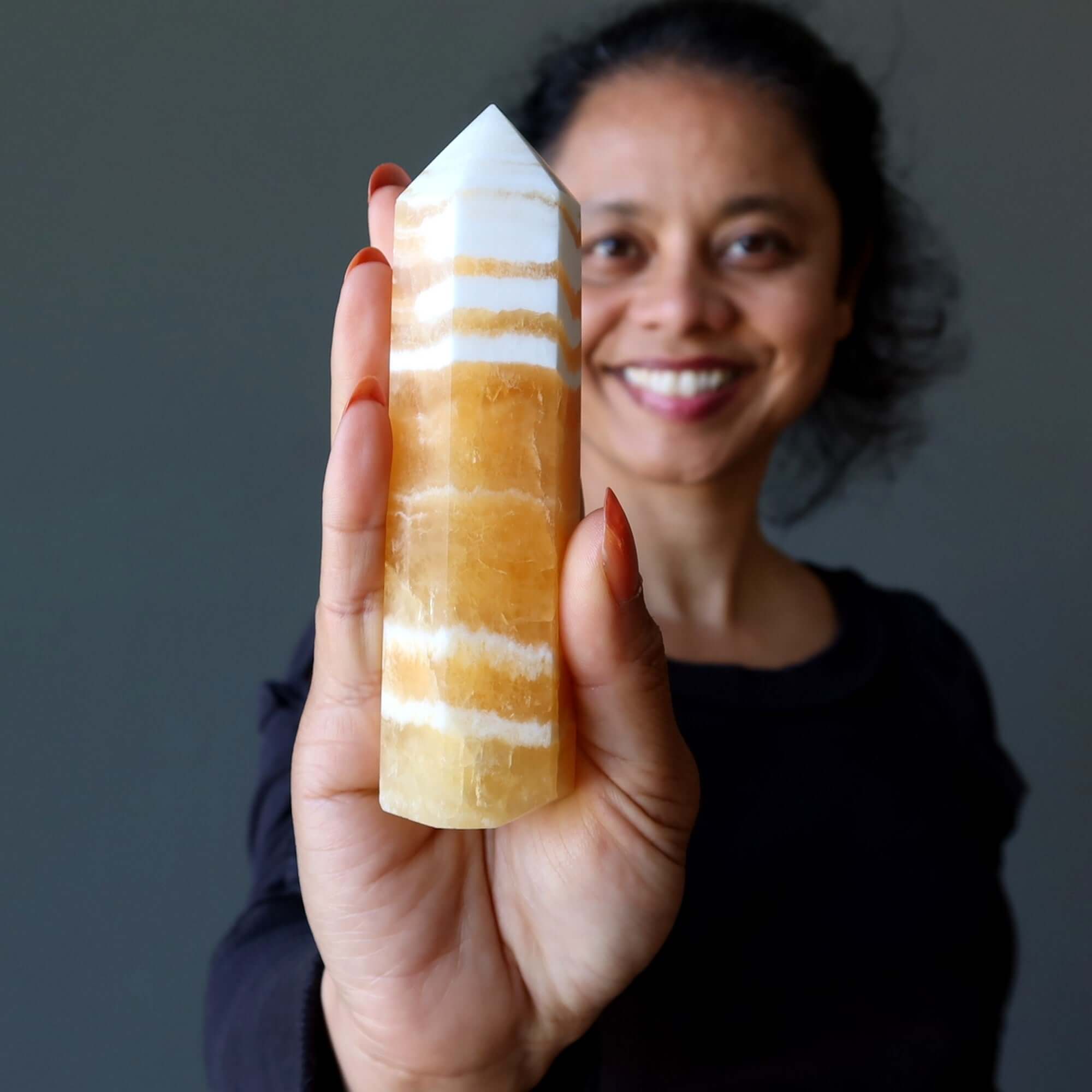 Orange Calcite tower wand beacon of confidence crystal held upright in hand for solar plexus chakra energy and self-esteem