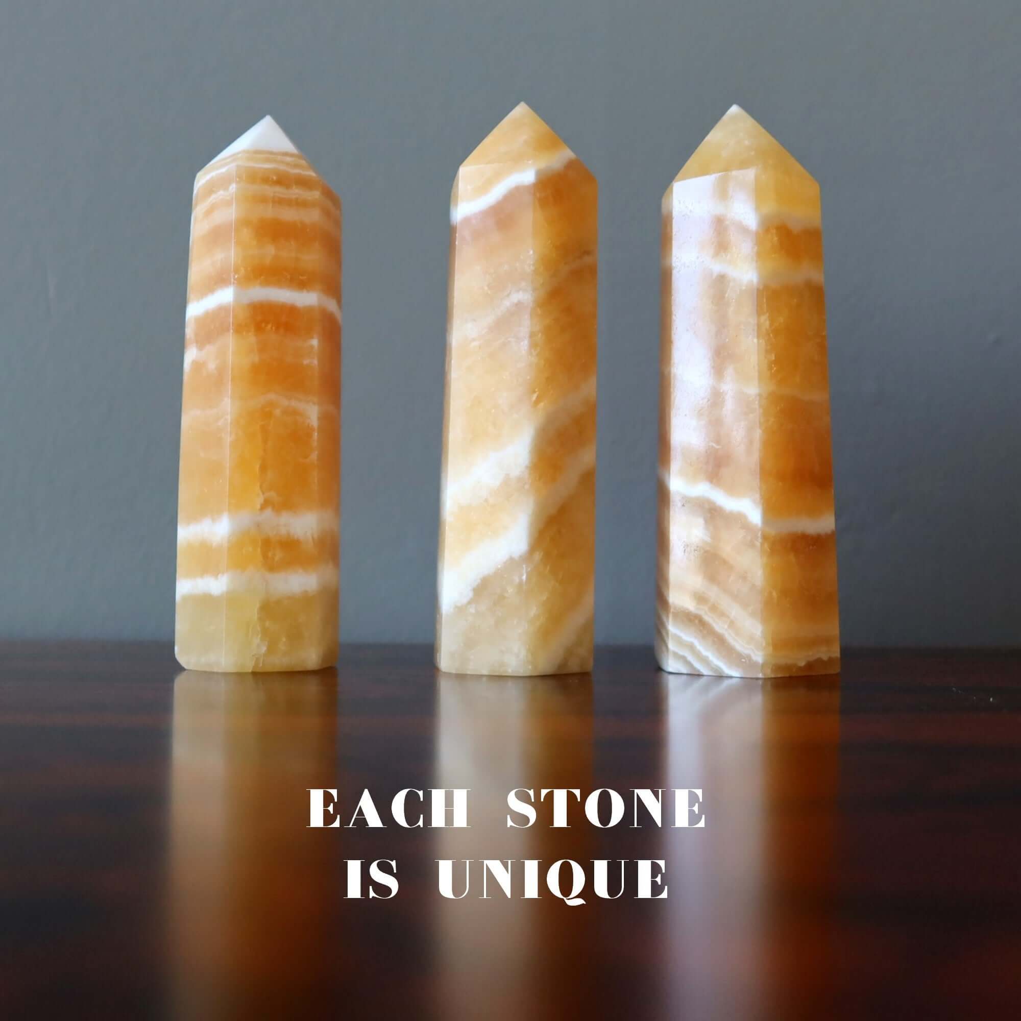 Orange Calcite tower wands showing unique striped patterns on a wooden surface, each stone is unique for confidence and solar plexus energy