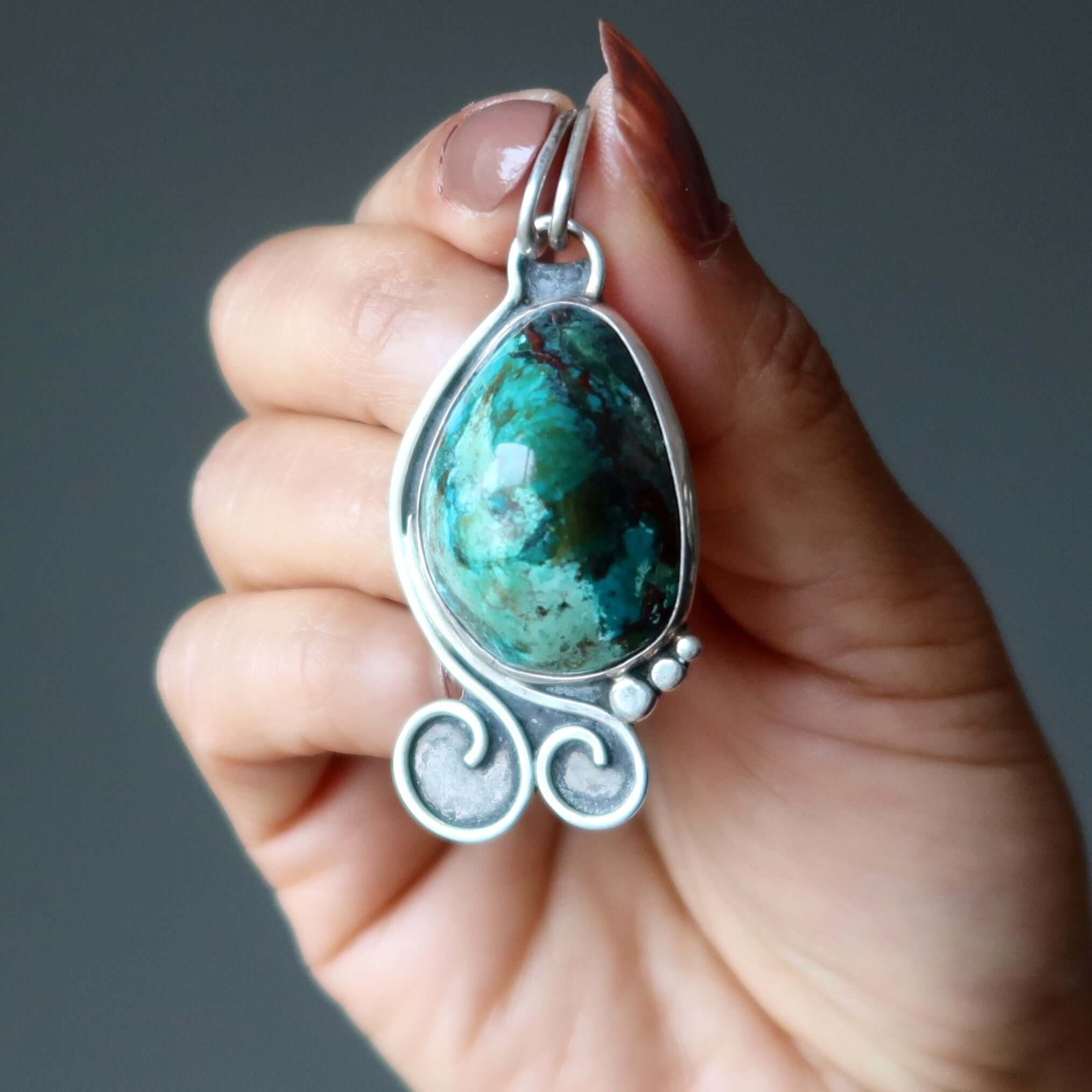 Chrysocolla Sonora Sunrise pendant in sterling silver with cuprite gemstone held in hand