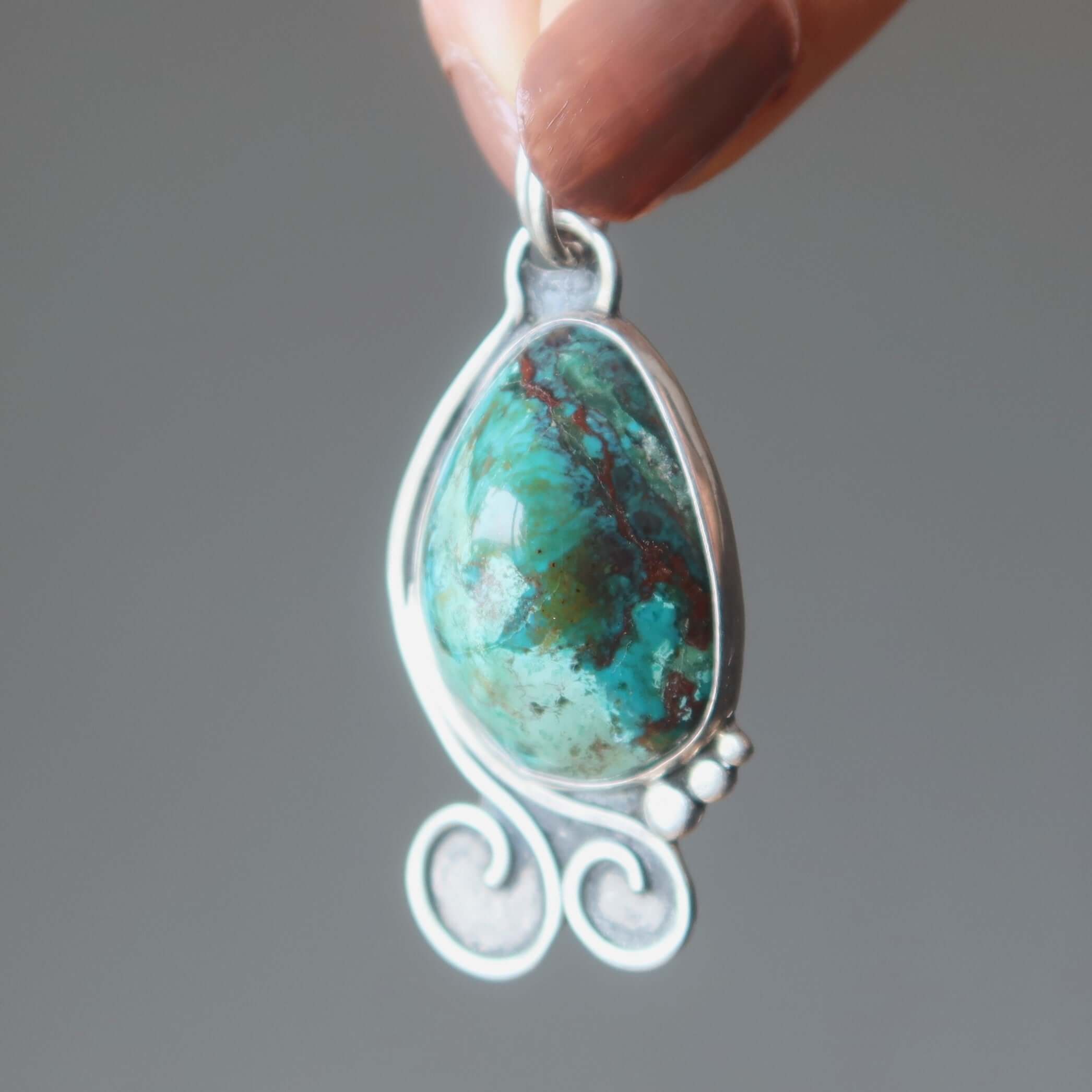 Chrysocolla pendant cuprite Sonora gem in sterling silver teardrop setting held between fingers
