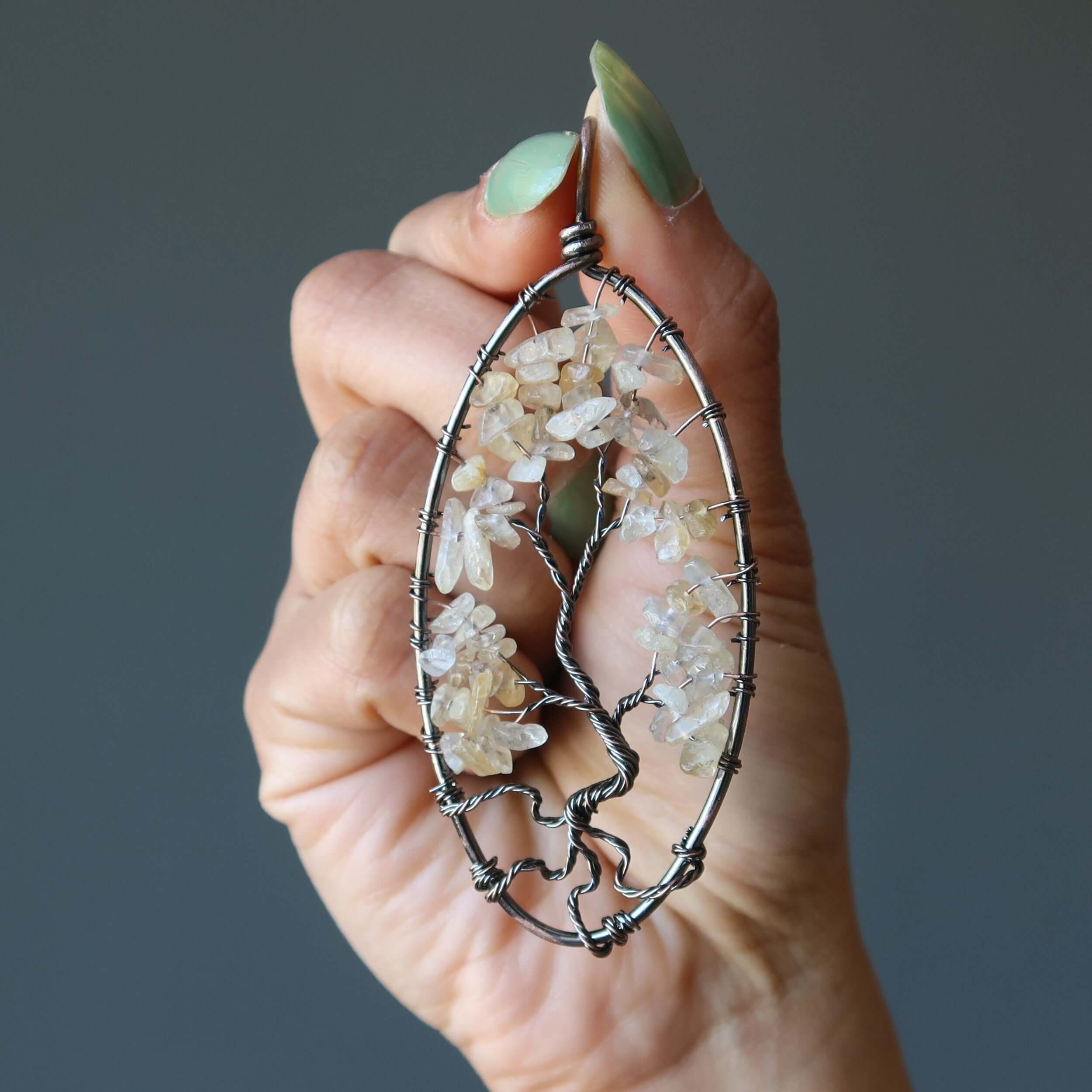 Citrine Tree of Life pendant with yellow gemstone chips in antiqued copper wire, oval statement necklace held in hand