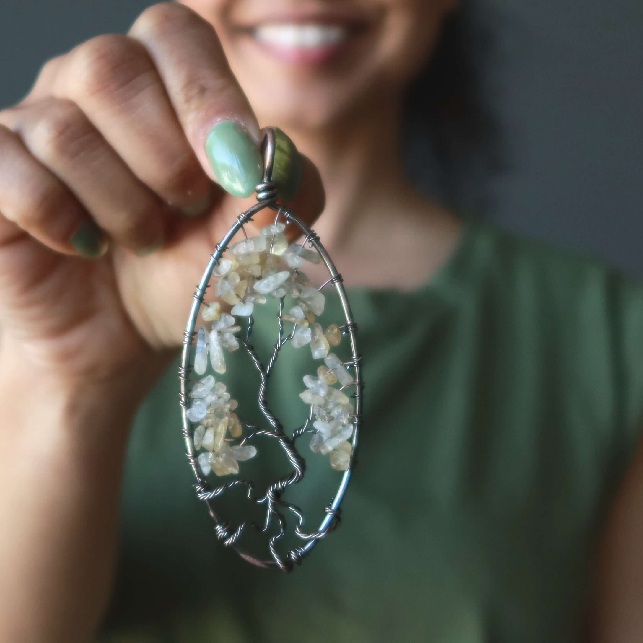 Citrine Tree of Life pendant with yellow gemstone chips in antiqued copper wire, held in hand for jewelry detail view