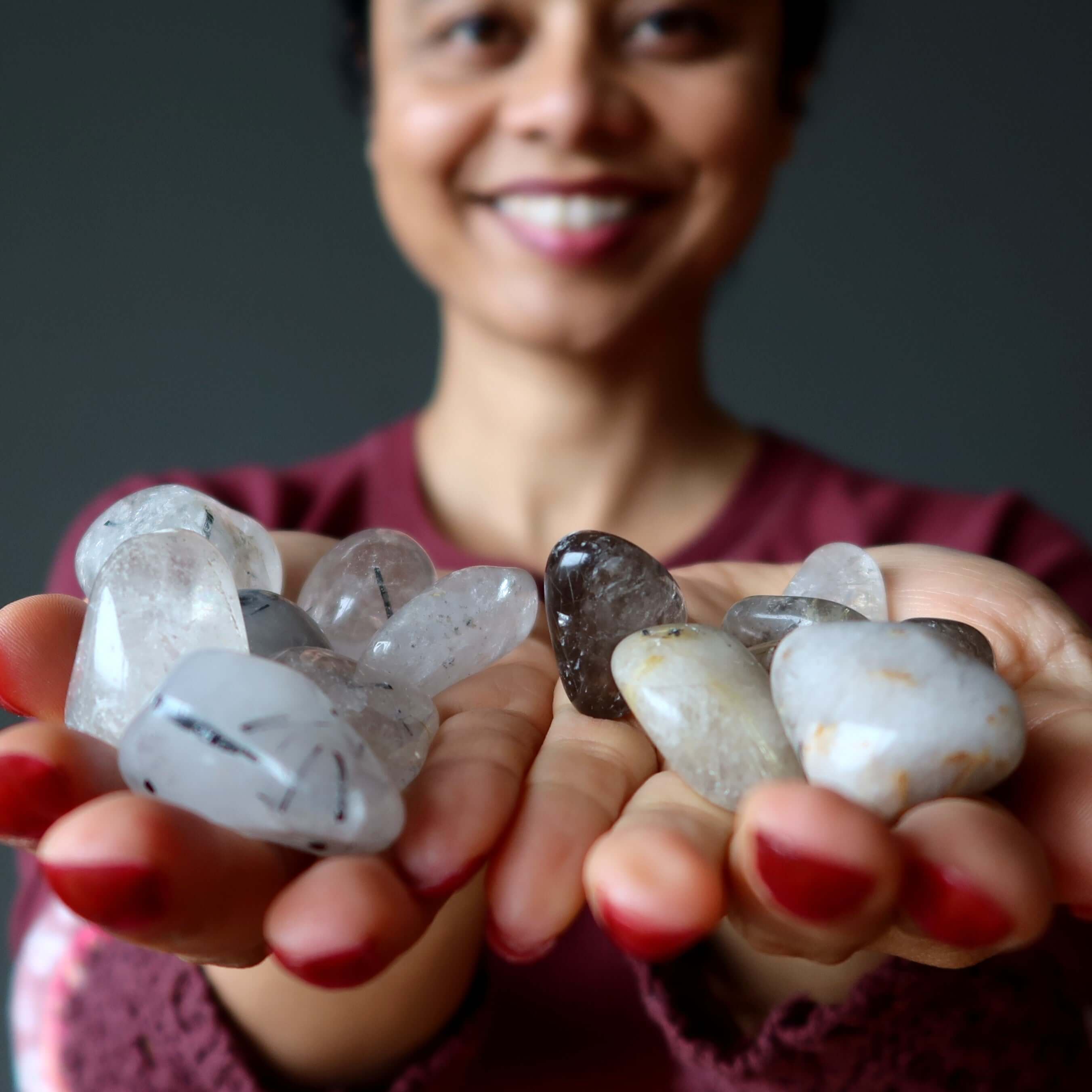 Tumbled Crown Chakra rutilated quartz stone set held in both hands for spiritual healing and aura balancing