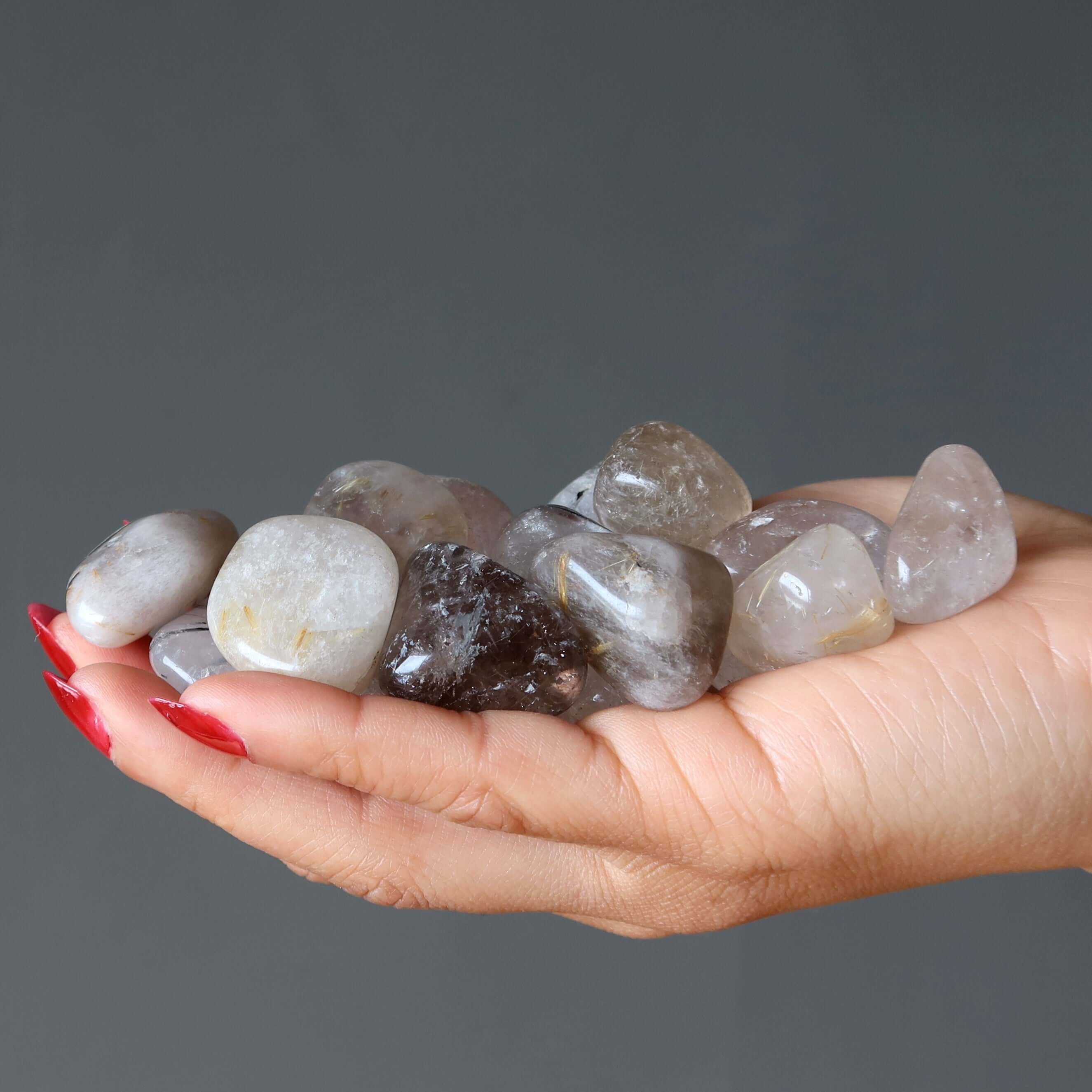 Hand holding Tumbled Stone Set Crown Chakra rutilated quartz and black tourmaline healing crystals