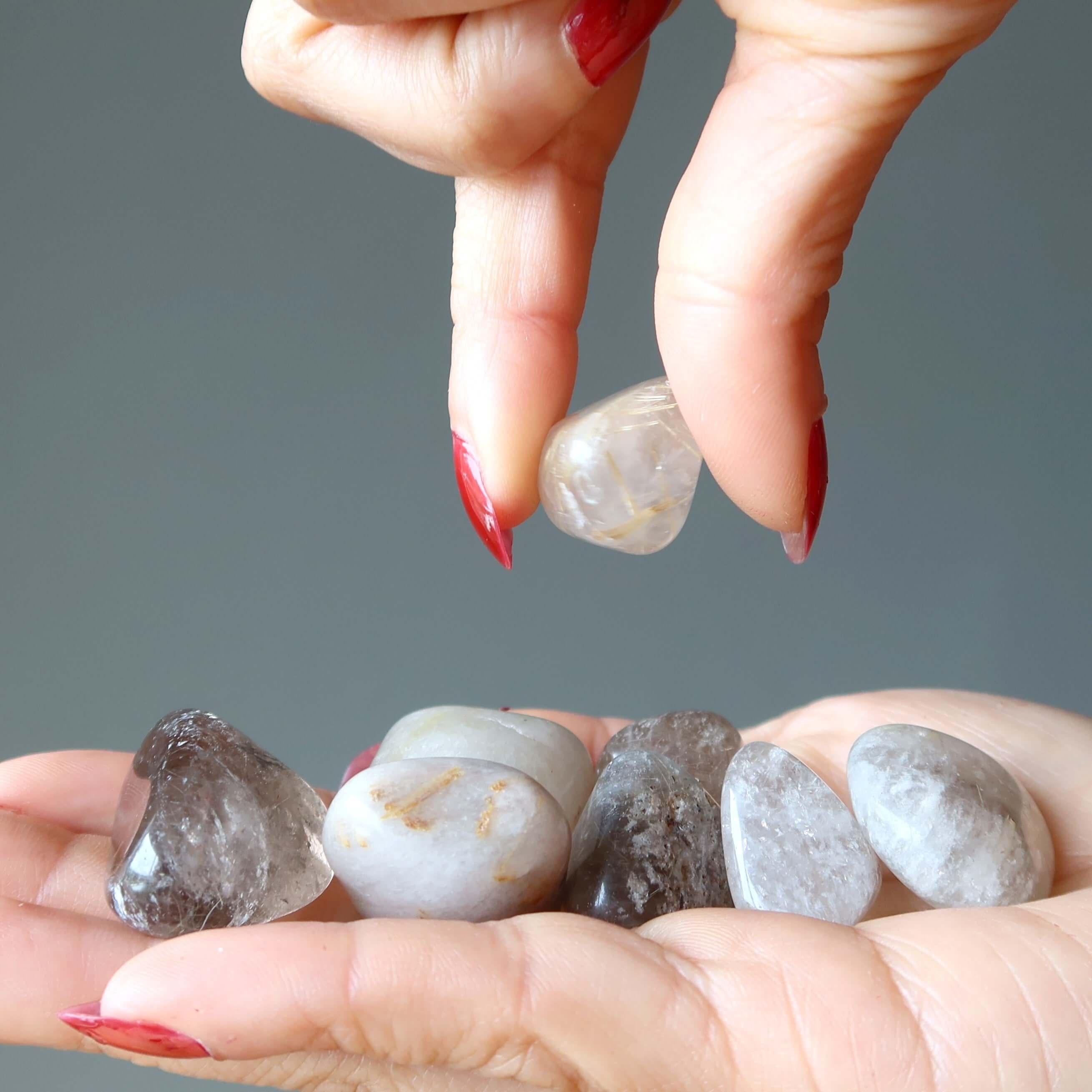 Hand holding Crown Chakra Tumbled Rutilated Quartz stone set for crystal healing and spiritual energy work