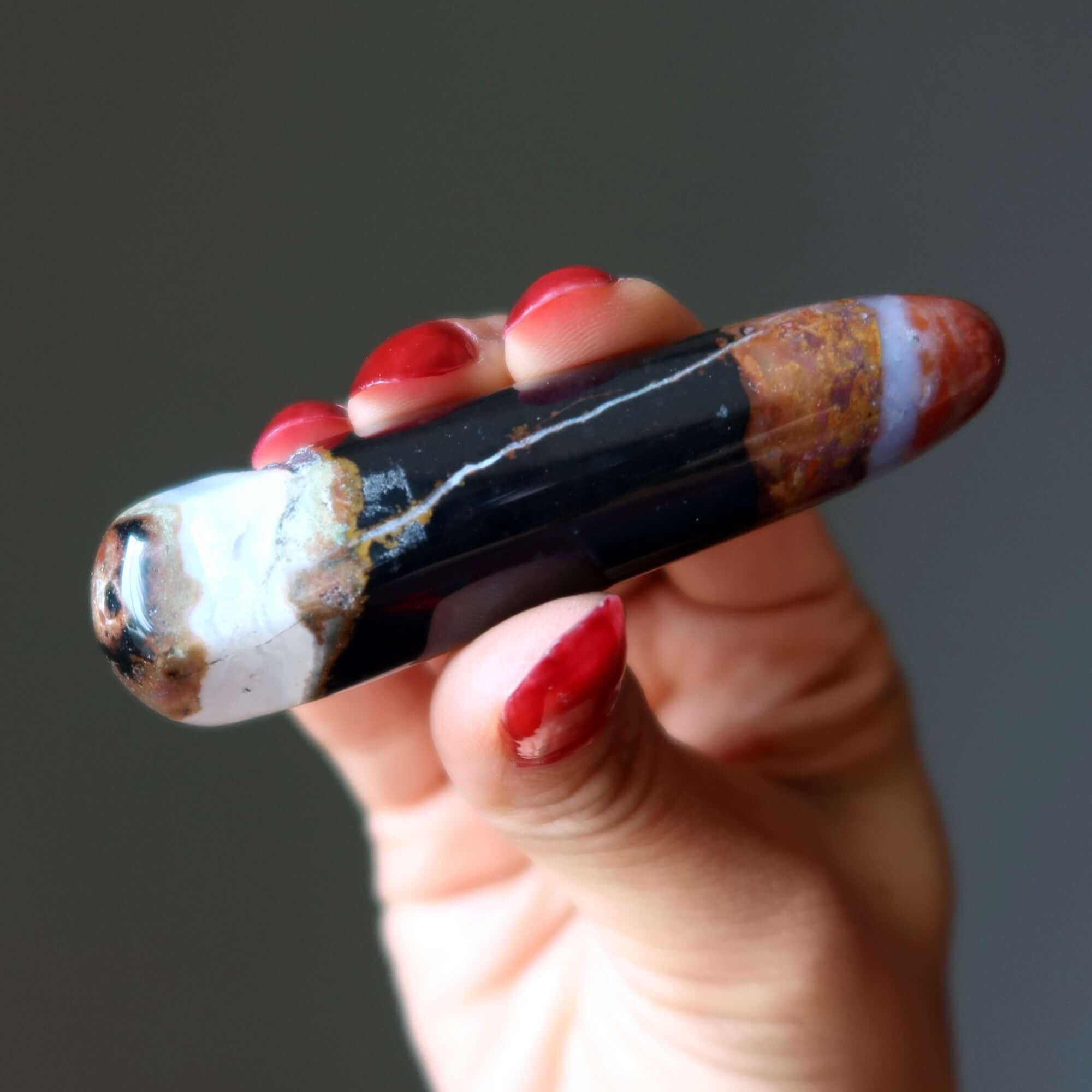 Hand holding colorful Jasper jasper massage wand earth energy stone for stress relief and soul nurturing