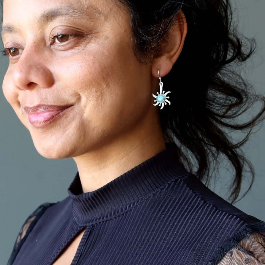 Woman wearing sterling silver Larimar sun earrings with blue gemstone, showcasing Larimar jewelry style