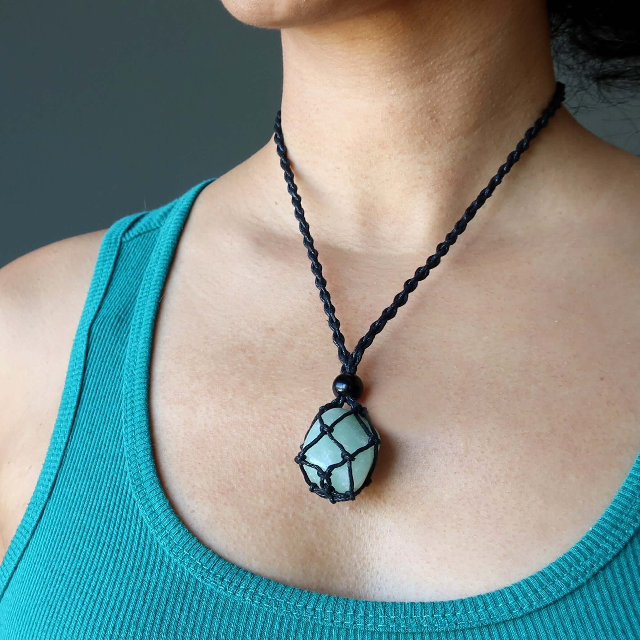 Money necklace set with green aventurine stone in black macrame netting worn on model’s neck