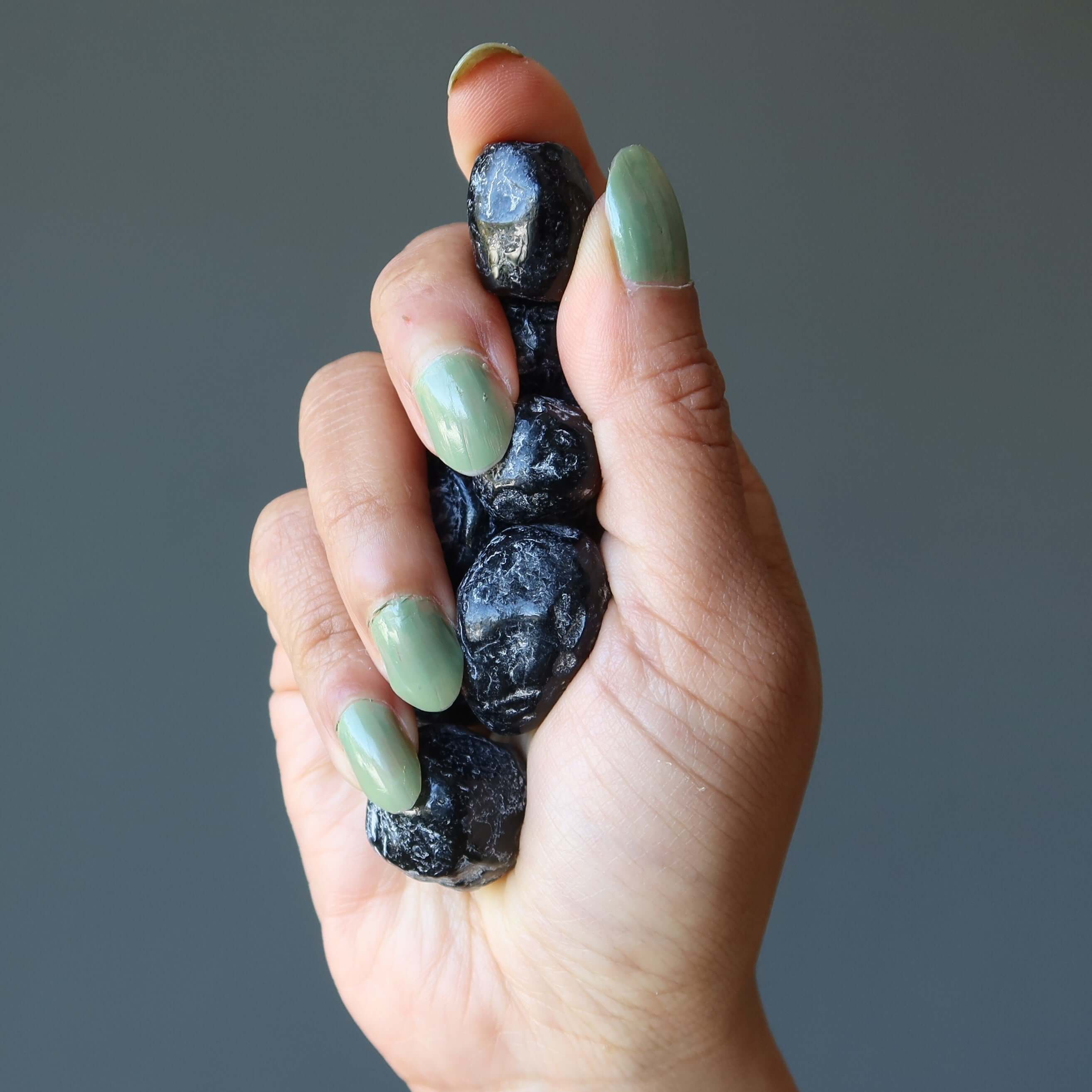 Hand holding Apache Tear Obsidian tumbled mourning stones for grief comfort and emotional healing