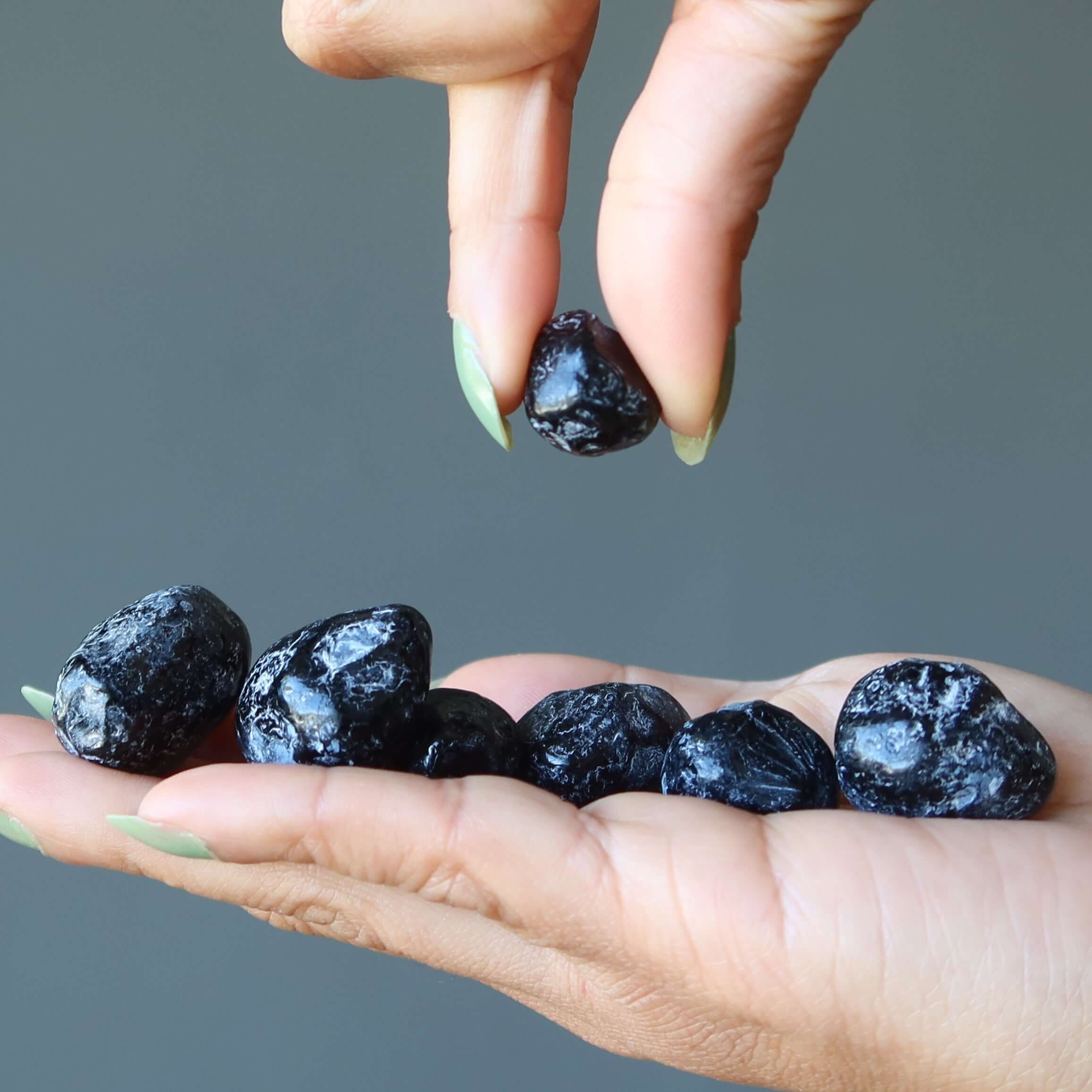 Apache Tear Obsidian tumbled mourning stones for grief comfort displayed in hand