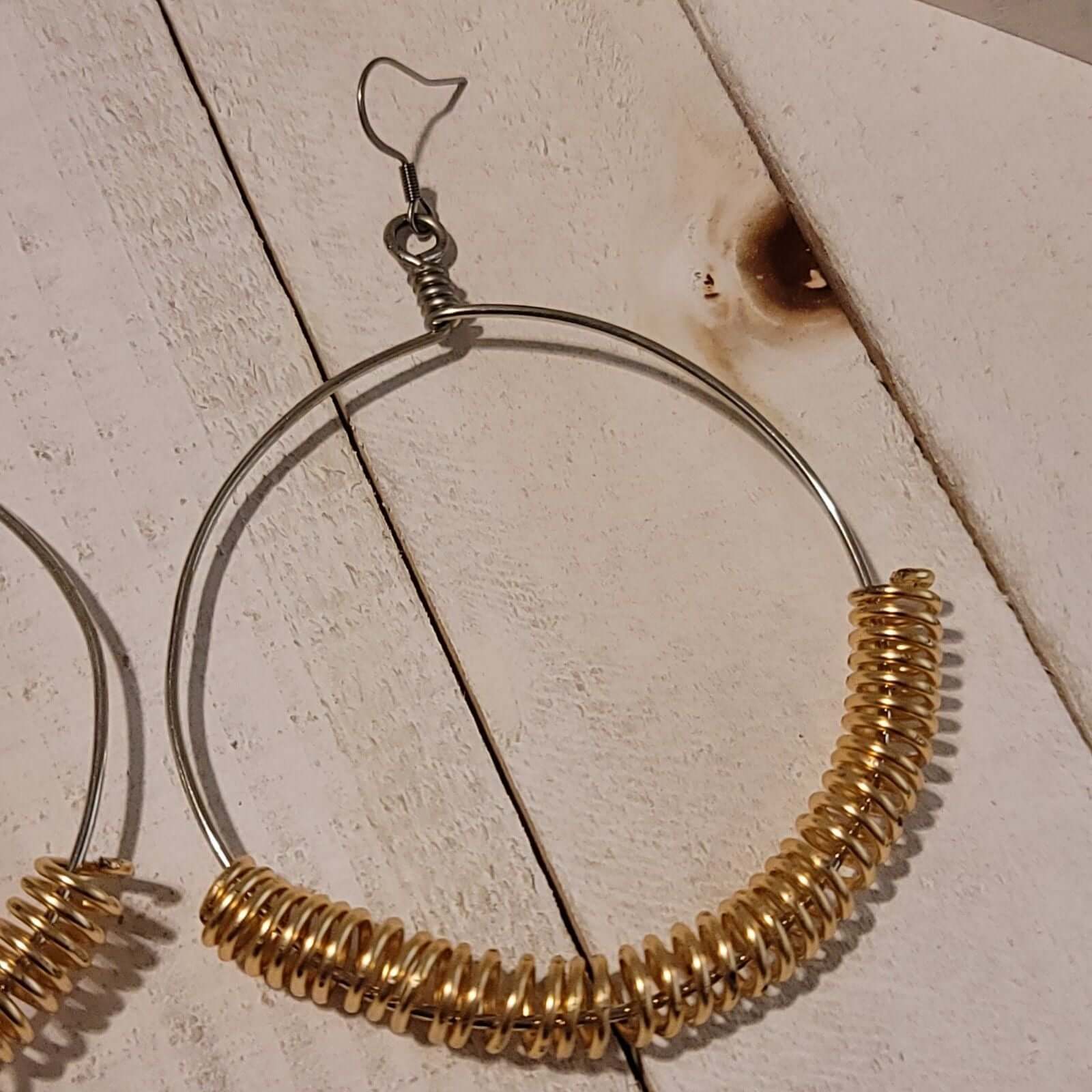 Handmade Gold Spring Hoop Earrings – Lightweight Wire Wrapped Hoops with gold coil accents on silver-tone hoop on rustic wood background