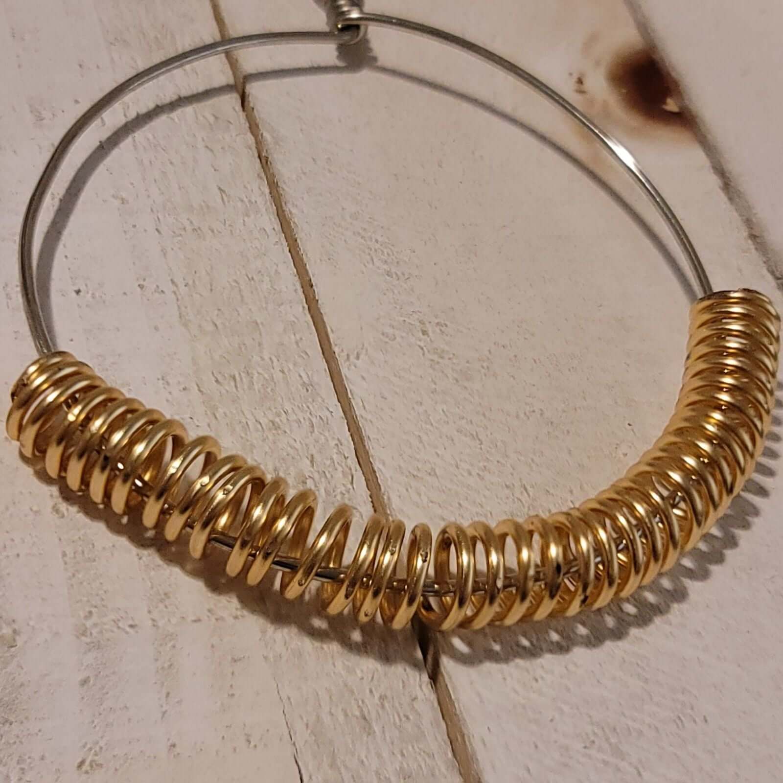 Handmade Gold Spring Hoop Earrings – Lightweight Wire Wrapped Hoops with gold coil accents on silver-tone base on rustic wood background