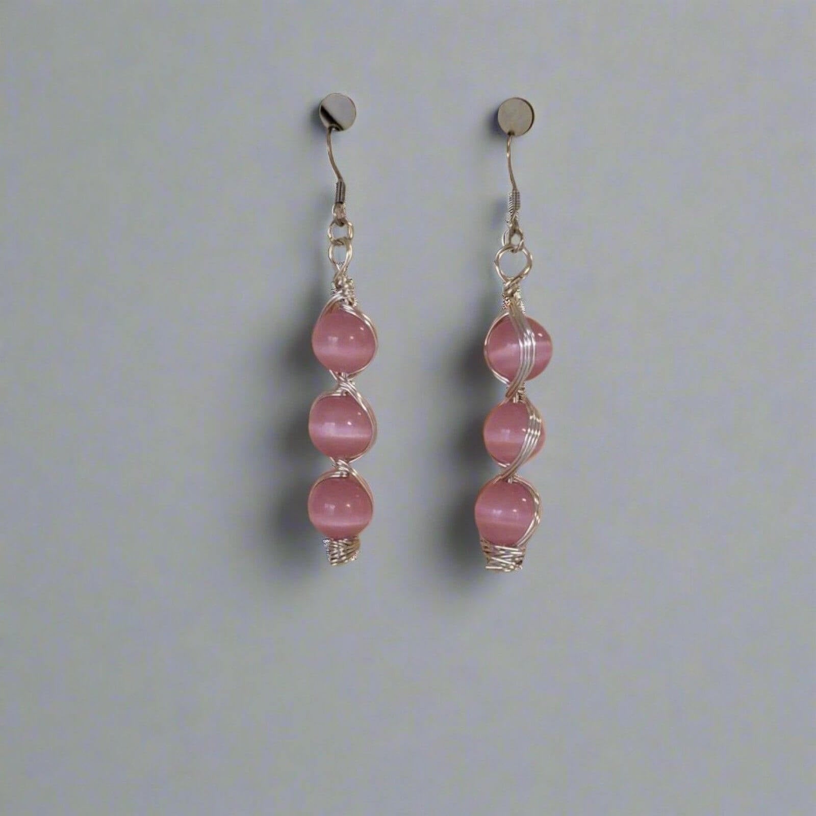 Alt Tag: Handmade Pink Cat’s Eye Bead Earrings – Wire Wrapped Dangle Jewelry with three stacked pink beads on silver-tone hooks