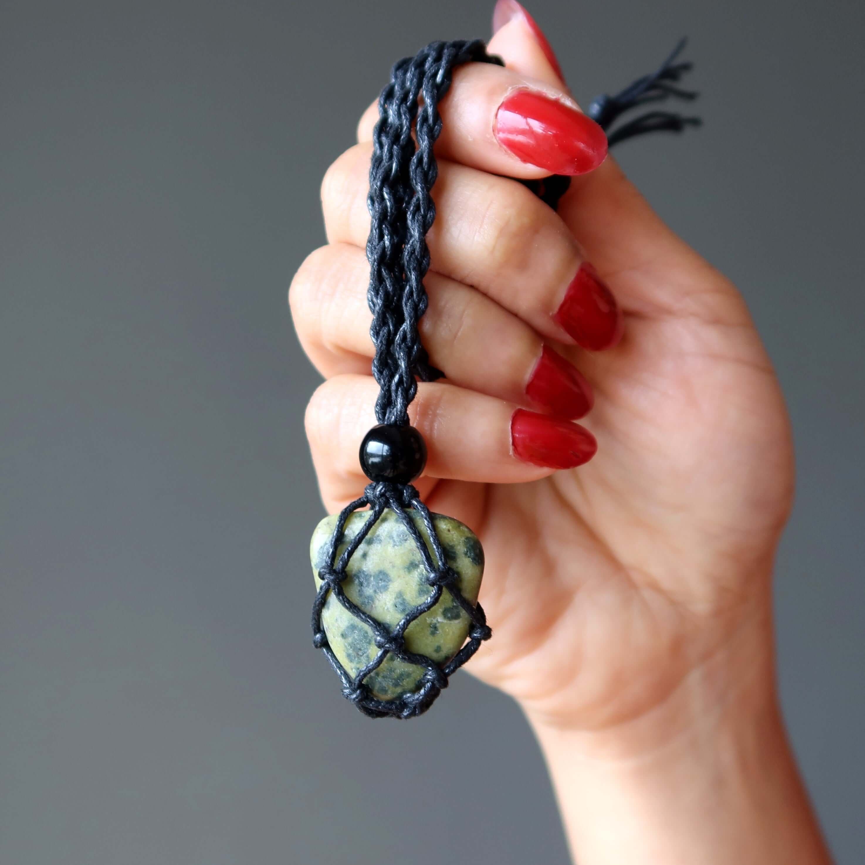 Serpentine necklace in black macrame net held in hand, green transformation stone pendant jewelry