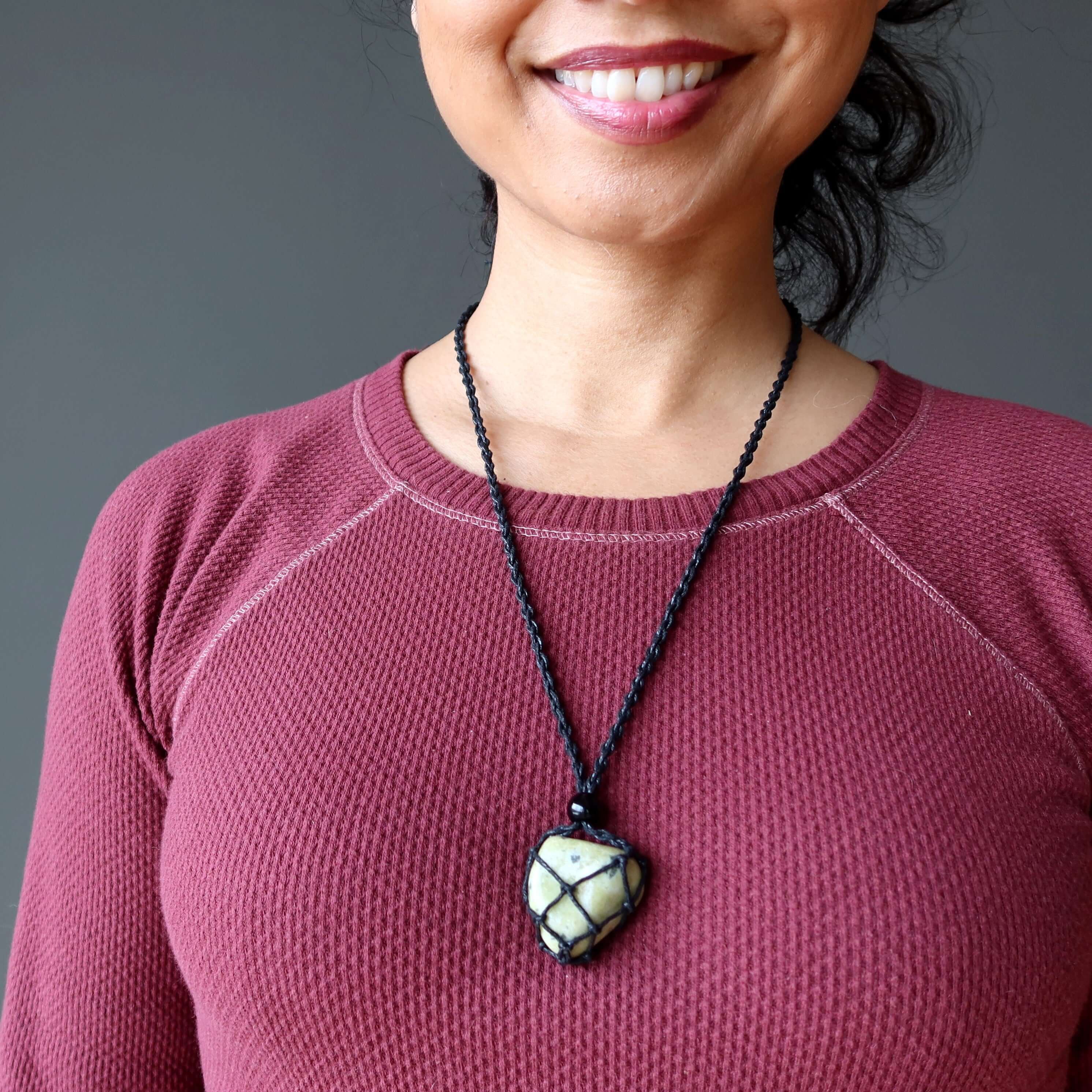 Serpentine necklace transformation stone in black macrame net on woman’s chest, adjustable cord healing crystal jewelry