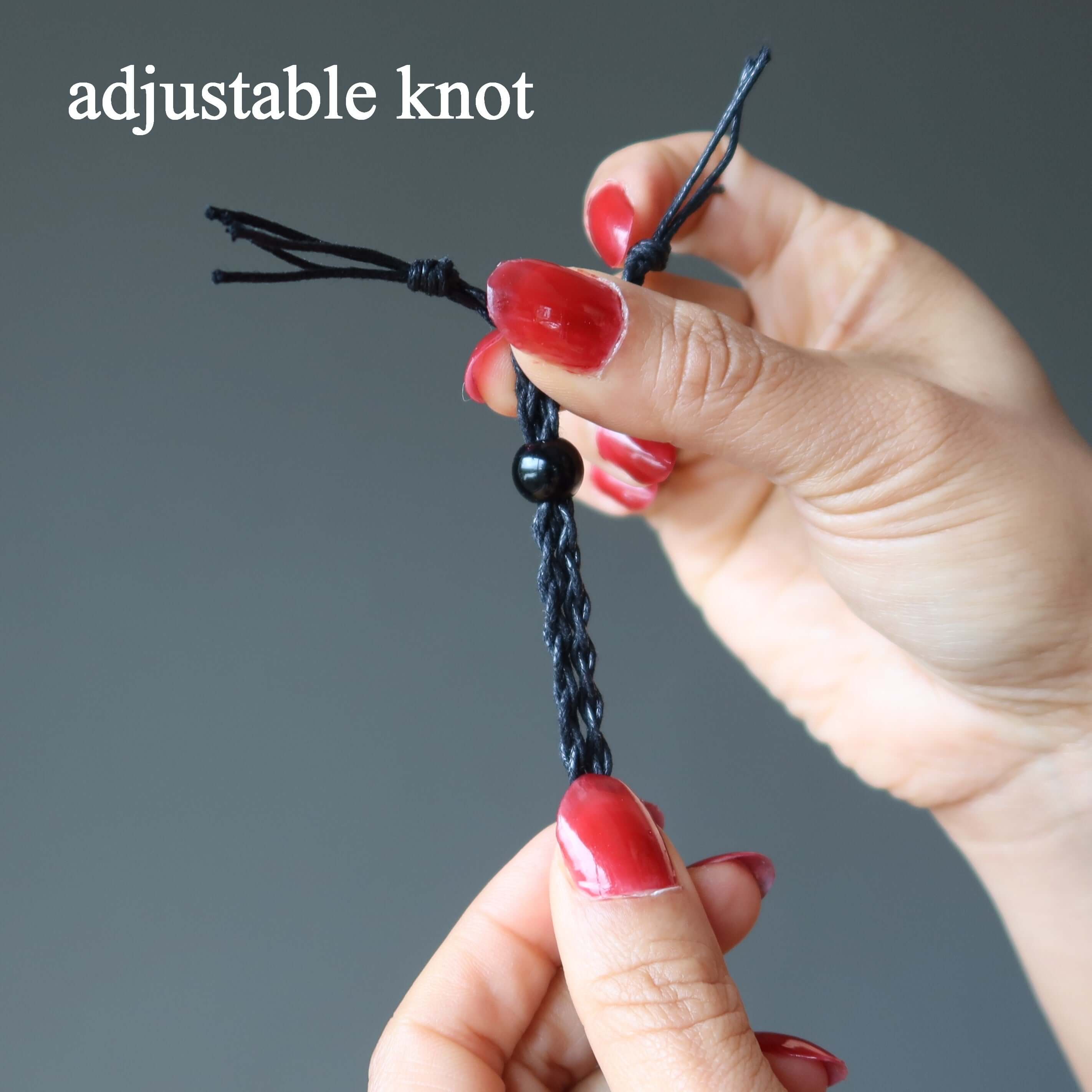 Adjustable knot on black macrame Serpentine necklace cord being tightened by hands